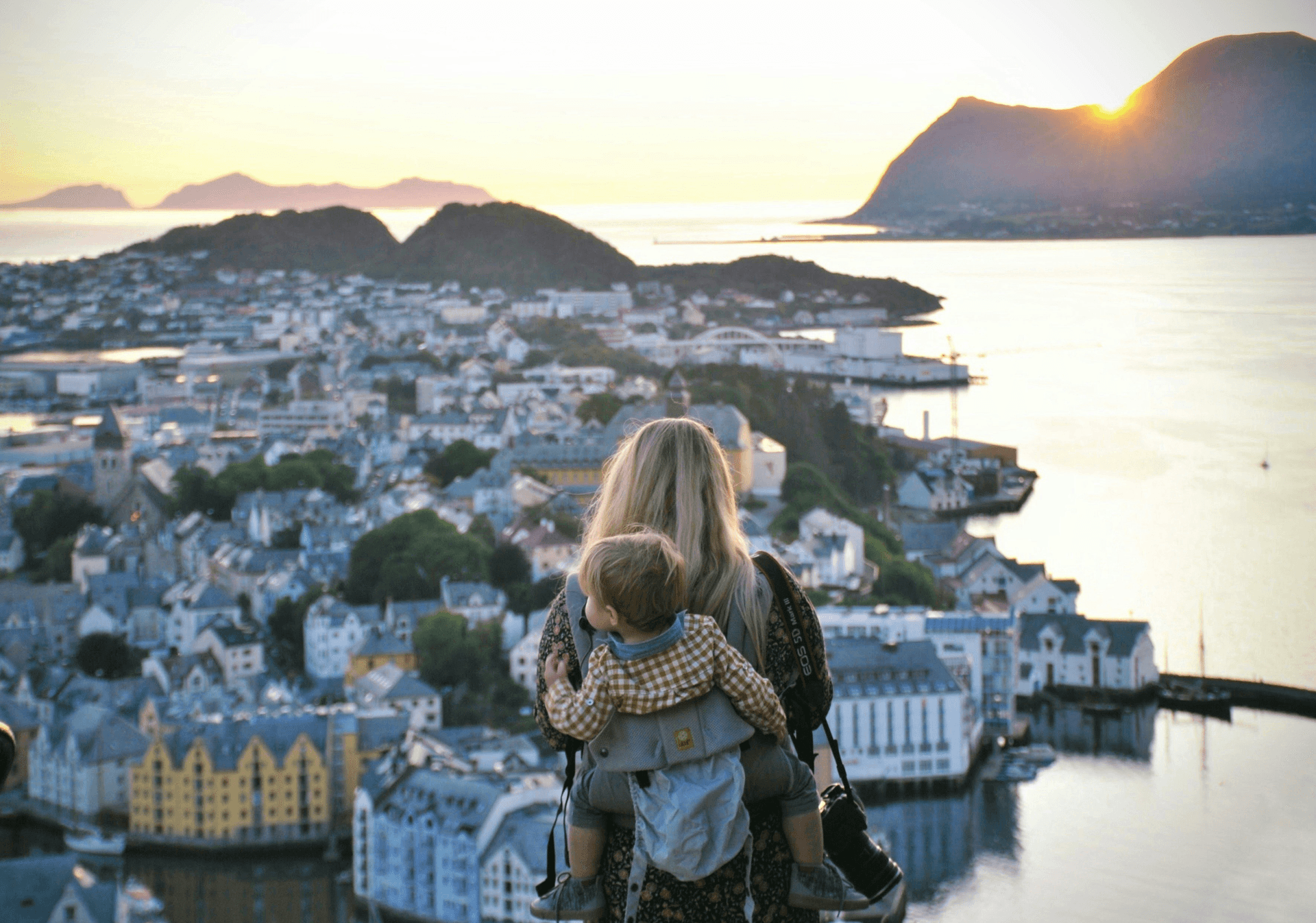 Parent and child overlooking Ålesund and the sea at sunset.
